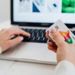 Close-up of hands using a laptop and holding a credit card for an online transaction.