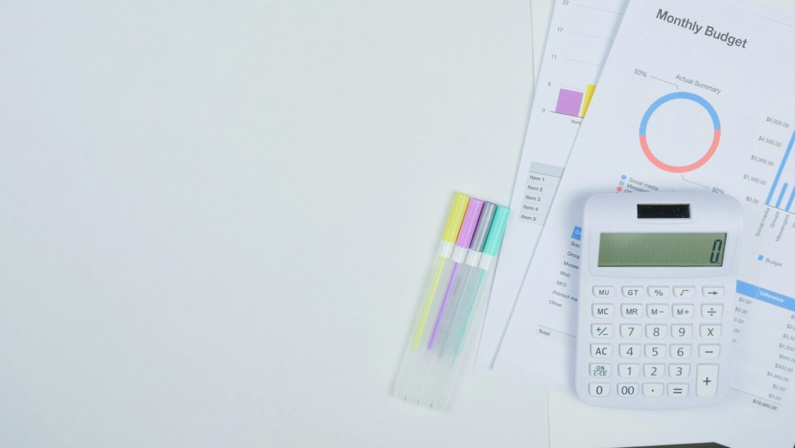 Minimalist office desk with a calculator, budget planning documents, and colorful pens.